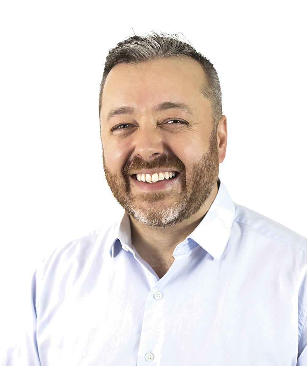 Justin Munsters, smiling, in a light blue button-down shirt